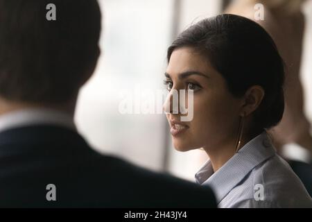 Testa colpo concentrata millenaria donna indiana parlando con il collega. Foto Stock