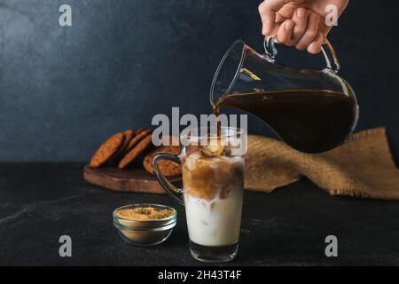 Donna che prepara il latte ghiacciato di hojicha su sfondo nero Foto Stock