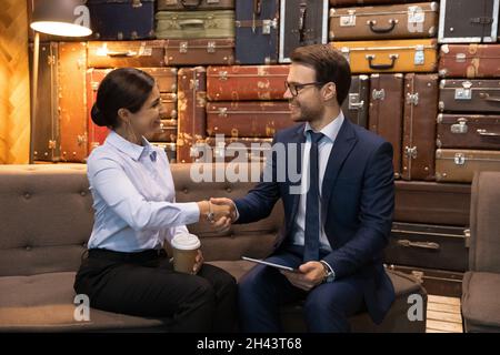 Felice giovane donna d'affari indiana che agita le mani con il partner maschile. Foto Stock