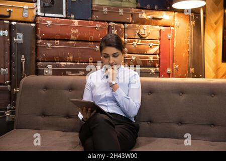 Concentrò la giovane donna d'affari indiana utilizzando il tablet digitale. Foto Stock