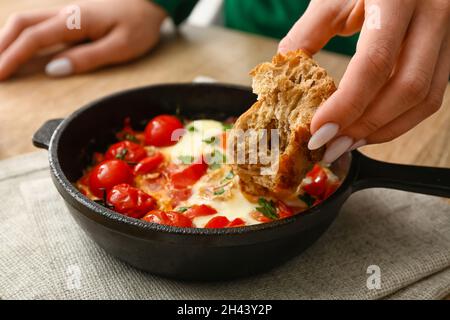 Donna che mangia Shakshouka gustoso a tavola Foto Stock