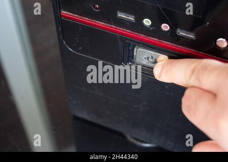 Man Finger pressione su un pulsante di spegnimento di un computer di casa. Foto Stock