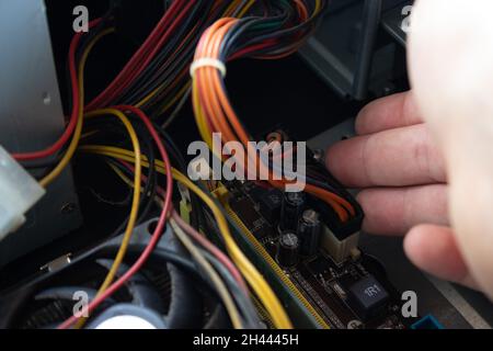 Man mano che mette i collegamenti elettrici di un computer nelle prese di destra per far funzionare correttamente il computer. Collegamenti dei cavi di alimentazione. Foto Stock