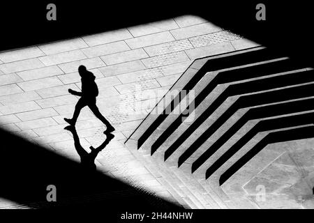 Shadow silhouette di ragazzo adolescente a piedi strada strada della città marciapiede, in bianco e nero dall'alto Foto Stock