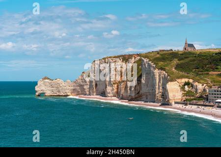 Etretat è meglio conosciuta per le sue scogliere di gesso, tra cui tre archi naturali e una formazione appuntita chiamata Aiguille o l'ago Foto Stock