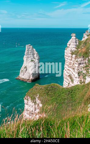 Etretat è meglio conosciuta per le sue scogliere di gesso, tra cui tre archi naturali e una formazione appuntita chiamata Aiguille o l'ago Foto Stock