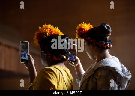 Tieton, Washington, Stati Uniti. 31 ottobre 2021. I membri del Balletto Folkloric della scuola superiore di Davis registrano una performance sui loro telefoni cellulari alla celebrazione della comunità dia de los Muertos a Tieton, Washington domenica 31 ottobre 2021. Tieton Arts & Humanities ospita la celebrazione annuale per ricordare gli amici e i membri della famiglia che sono morti e per aiutare a sostenere il loro viaggio spirituale. Credit: Paul Christian Gordon/Alamy Live News Foto Stock