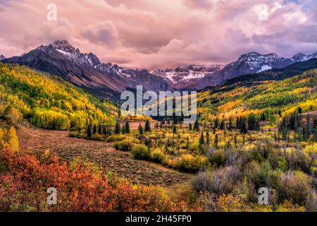 Una valle colorata con l'East Fork di Dallas Creek e Willis Swamp, con colori autunnali spettacolari sotto il Monte Sneffels e le nuvole al tramonto in modo oscure nella SA Foto Stock