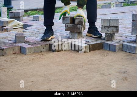 posa di lastre di pavimentazione sulla sabbia con le mani Foto Stock