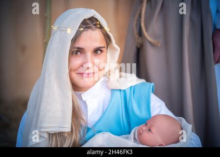 Donna raffigurante la Vergine maria di fronte alla macchina fotografica e tenendo Gesù Foto Stock