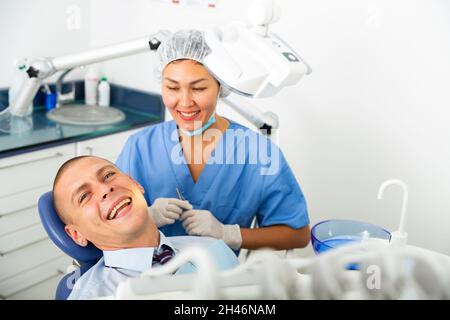 Sorridente uomo soddisfatto paziente visita dentista Foto Stock