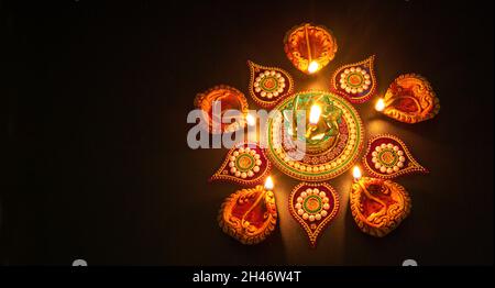 Tradizionali lampade Diya in argilla Diwali illuminate su sfondo scuro con rangoli Foto Stock