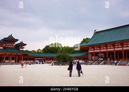 Vista sul cortile interno del Santuario di Heian con folla di persone che camminano. Sala principale, torre Byakko-rou e sfondo cielo nuvoloso. Foto Stock