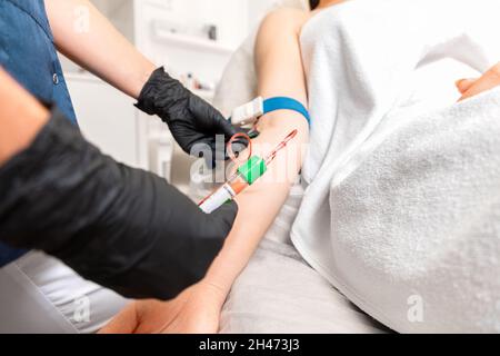 Cosmetologia e salute. L'estetista effettua il campionamento del sangue dalla mano del cliente per la procedura di plasmolifting. Procedura di ringiovanimento professionale in Foto Stock