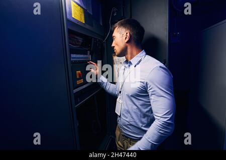 Tecnico maschile esperto che esegue il monitoraggio della tensione nel data center Foto Stock