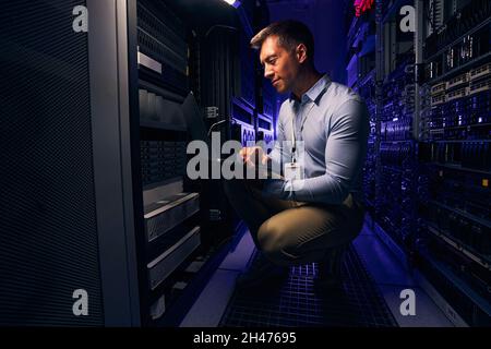 Il dipendente controlla le apparecchiature hardware nella sala server Foto Stock