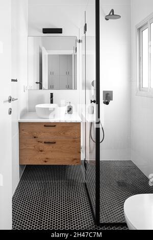 Bagno, armadio in legno marrone, illuminazione e varie piastrelle Foto Stock