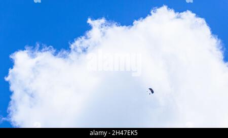 Skydiving in tandem volo da solista da atleta di skydiver in lontananza contro cielo blu e paesaggio acumolus nuvola. Foto Stock