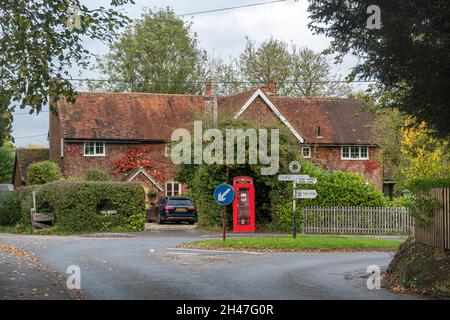 Vista del villaggio di Sherborne St John in Hampshire, Inghilterra, Regno Unito, con il cartello con le dita, telefono rosso e cottage Foto Stock