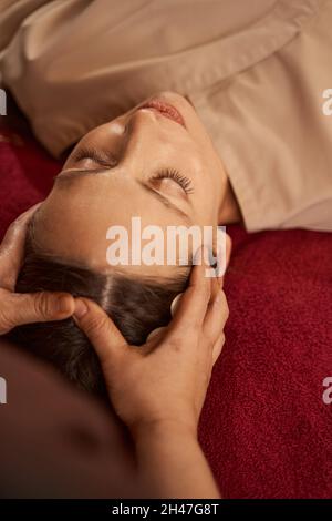 Giovane cliente spa con il suo cuoio capelluto massaggiato Foto Stock