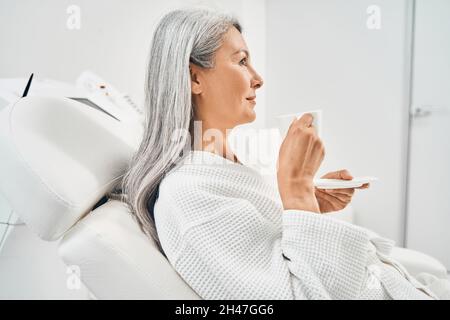 Attraente persona femminile seduta su sedia di dermatologia Foto Stock