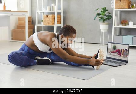 Felice giovane donna che ha sport workout a casa con il suo istruttore in linea di idoneità Foto Stock