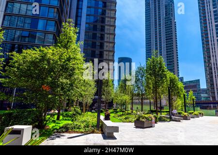 Persone che si rilassano in South Quay Square circondato da skyslapers di nuova costruzione, South Quay, Tower Hamlets London, Regno Unito Foto Stock