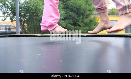 una giovane donna e una giovane ragazza stanno saltando su un ariete, primo piano. Le gambe galleggiano in aria dopo aver saltato su un trampolino. Divertimento per tutta la famiglia, intrattenimento e sport Foto Stock