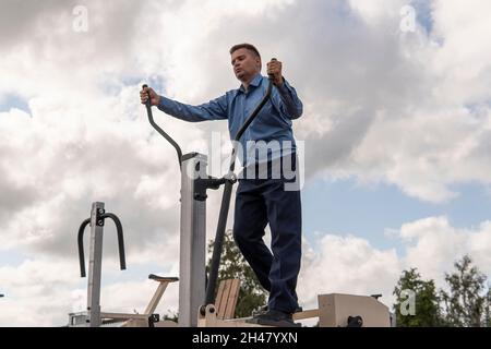 Bel giovane uomo in abito nero, camicia bianca e cravatta in palestra Foto Stock