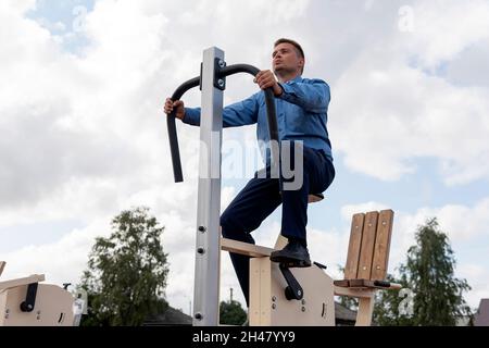 Uomo d'affari che fa le esercitazioni sugli addestratori nella palestra. Foto Stock