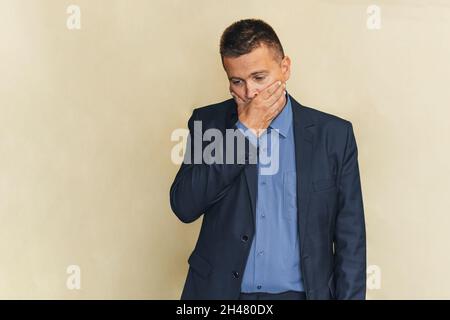 Confusione, uomini, affari. Un uomo tiene la bocca con le mani un'emozione di delusione e vergogna, un dente malato sta soffrendo. Foto Stock