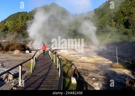 Lagoa das Furnas e Fumarolas, donna che cammina su un sito di sorgenti termali e fumarole bollenti sull'isola di Sao Miguel, Azzorre, Portogallo Foto Stock