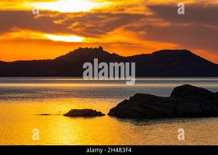 Vista sul tramonto d'oro colorato: La costa della Sardegna settentrionale e le lontane isole di Caprera e la Maddalena con il cielo rosso brillante e la domenica. Foto Stock