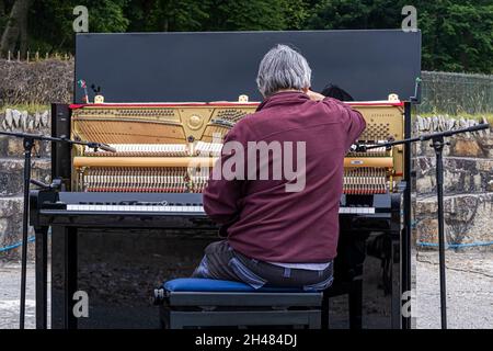 Un sintonizzatore per pianoforte che sintonizza un pianoforte verticale in preparazione di un recital per pianoforte all'aperto. Foto Stock