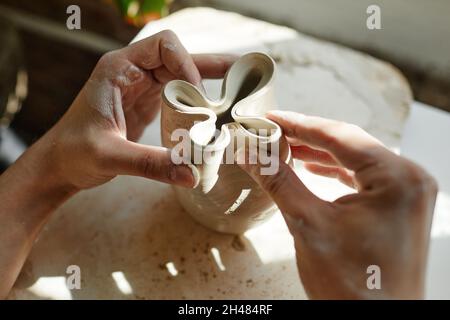 Primo piano delle mani femminili che modellano la ciotola di ceramica alla luce del sole, spazio di copia Foto Stock