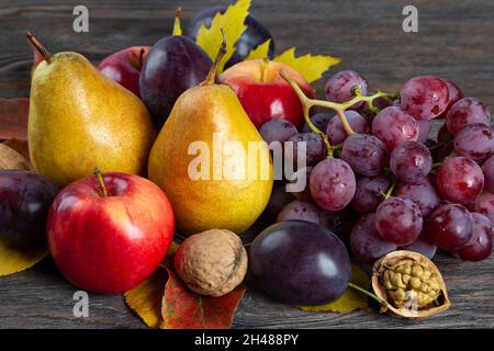 Autunno ancora vita con noci, uva, pere e mela. Frutta e noci su sfondo di legno marrone Foto Stock