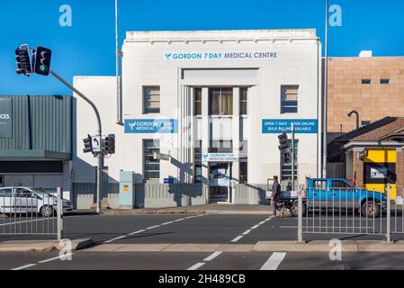 Un uomo cammina dietro una auto parcheggiata di fronte al patrimonio elencato Gordon Medical Center, ex Commonwealth Bank, a Gordon Sydney, Australia Foto Stock