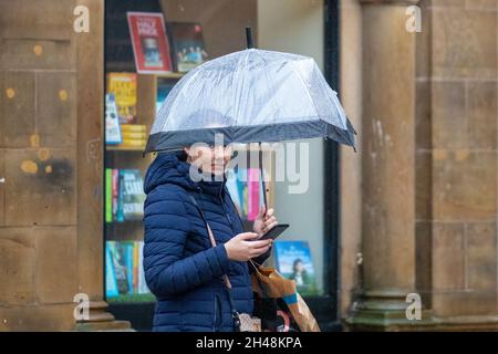 Venti forti e donna che trasportano ombrello rosa rovesciato a Preston, Lancashire, Regno Unito. 1 novembre 2021. Tempo britannico; negozi, shopping in una giornata bagnata e ventosa nel centro di Preston. Credit: MediaWorlImages/AlamyLiveNews Foto Stock