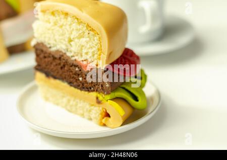 Pezzo della torta Burger, Madeira e torta stratificata di spugna di cioccolato, riempito con glassa ricoperta di glassa morbida e decorazioni di zucchero commestibile, torta i Foto Stock