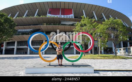 23 LUGLIO 2021 - TOKYO, GIAPPONE: Fotografo ufficiale Mickael CHAVET di fronte agli anelli olimpici al Japan National Stadium davanti al Tokyo 2 Foto Stock