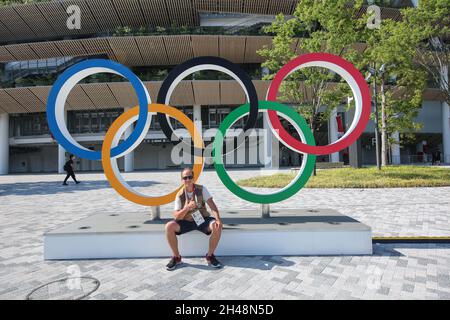 23 LUGLIO 2021 - TOKYO, GIAPPONE: Fotografo ufficiale Mickael CHAVET di fronte agli anelli olimpici al Japan National Stadium davanti al Tokyo 2 Foto Stock