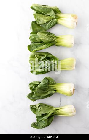 Una linea verticale di cluster bok choy su sfondo bianco. Foto Stock