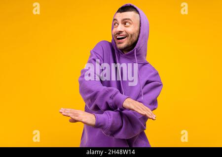 Foto ritratto giovane uomo vestito viola sportivo ballare rilassante aspetto copyspace isolato vibrante colore giallo sfondo Foto Stock