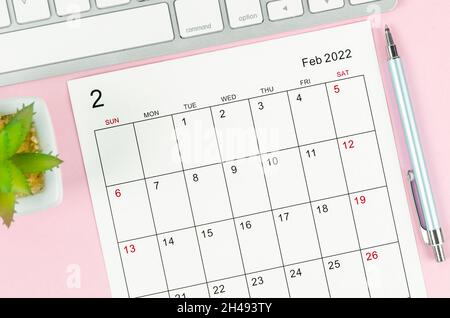 Il foglio di calendario di febbraio 2022 con tastiera computer su sfondo rosa. Foto Stock