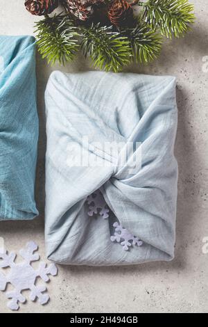 Articoli regalo in tessuto per Natale su sfondo grigio, vista dall'alto. Concetto di zero rifiuti. Stile Furoshiki. Foto Stock