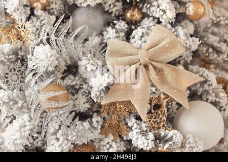 Primo piano foto di palline giocattolo in argento e oro su albero di Natale di lusso innevato con grande arco dorato Foto Stock