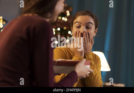 Ragazza felice che riceve un bel regalo di Natale da sua madre Foto Stock