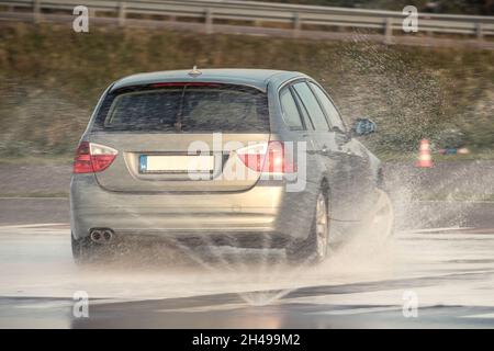 L'auto scivola su un terreno di allenamento professionale bagnato durante un percorso di guida sicuro Foto Stock