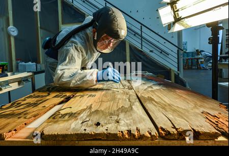 01 novembre 2021, Brandeburgo, Wünsdorf: Holger Müller, restauratore qualificato, lavora in tuta protettiva nel laboratorio di restauro del Landesamt für Denkmalpflege und Archäologisches Landesmuseum (BLDAM) su una pittura a figure di un teatro barocco allestito dal Monastero di Neuzelle. Grazie al generoso sostegno a lungo termine del commissario federale per la cultura e i mezzi di comunicazione (BKM), l'Ostdeutsche Sparkassensstiftung con lo Sparkasse Oder-Spree e la volontà del Ministero della scienza, della ricerca e della cultura (MWFK), l'Ufficio di Stato di Brandeburgo per la conservazione dei monumenti An Foto Stock