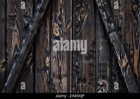 Tavole di legno di colore marrone scuro primo piano. La struttura della superficie di legno. Assi bruciati sfondo verticale e diagonale. Tessitura di legno scuro, weath Foto Stock